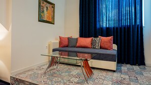 A living room with a sofa, patterned floor, and a painting on the wall.