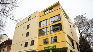 A yellow building with the sign "Hotel Elegance" on the front.
