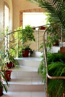 Una escalera con macetas, barandilla de metal y pared de piedra.