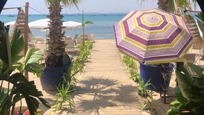 A wooden pathway leading to a beach with palm trees and beach chairs. - Residence Hammamet (Hammamet)