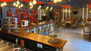 A restaurant with a bar area, red shelving units, and hanging light fixtures. - Residence Hammamet (Hammamet)