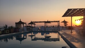 A serene pool area with umbrellas and lounge chairs, reflecting the sunset. - Residence Hammamet (Hammamet)