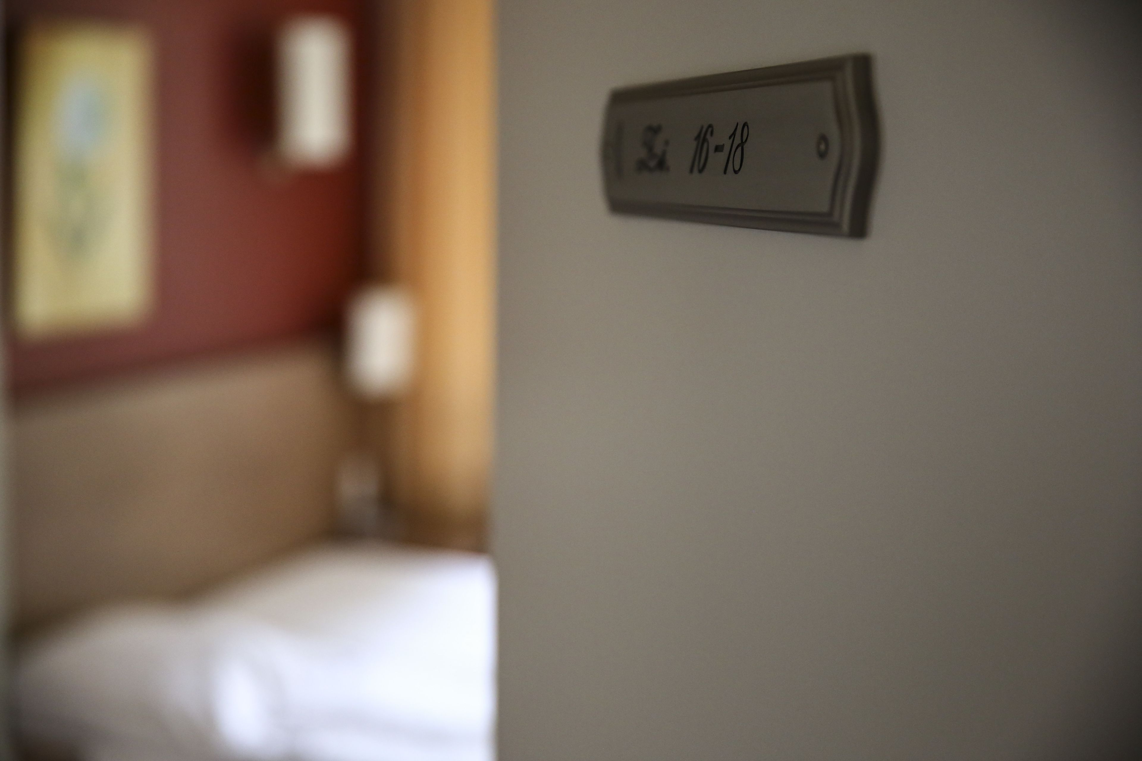 A room with a bed and a wall-mounted sign indicating room number 16-18.