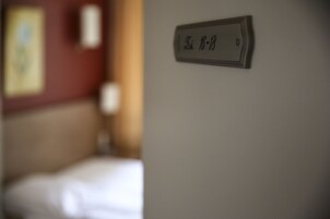 Ein Zimmer mit einem Bett und einem an der Wand befestigten Schild, das die Zimmernummer 16-18 anzeigt.