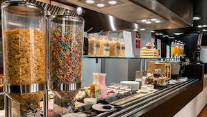 A buffet area with cereal and cereal bars, a coffee station, and various food items.