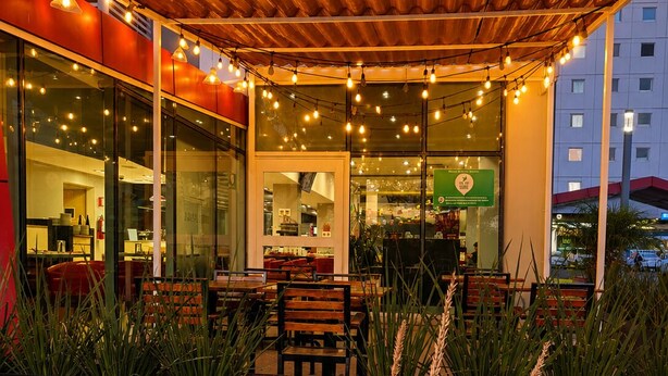 An outdoor seating area with tables and chairs, a covered patio, and potted plants.