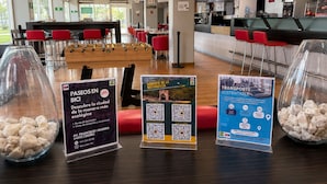 A modern restaurant with red chairs, a foosball table, and clear signage for bike rental and sustainable transport options.