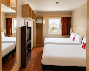 A hotel room with two beds, a TV, a wardrobe, and a window with curtains. - ibis Aguascalientes Norte (Aguascalientes)