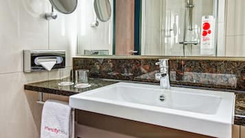 A modern bathroom with a white sink, granite countertop, and a large mirror.
