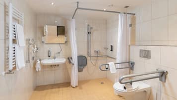 Un baño moderno con ducha, inodoro, lavamanos y barras de apoyo.