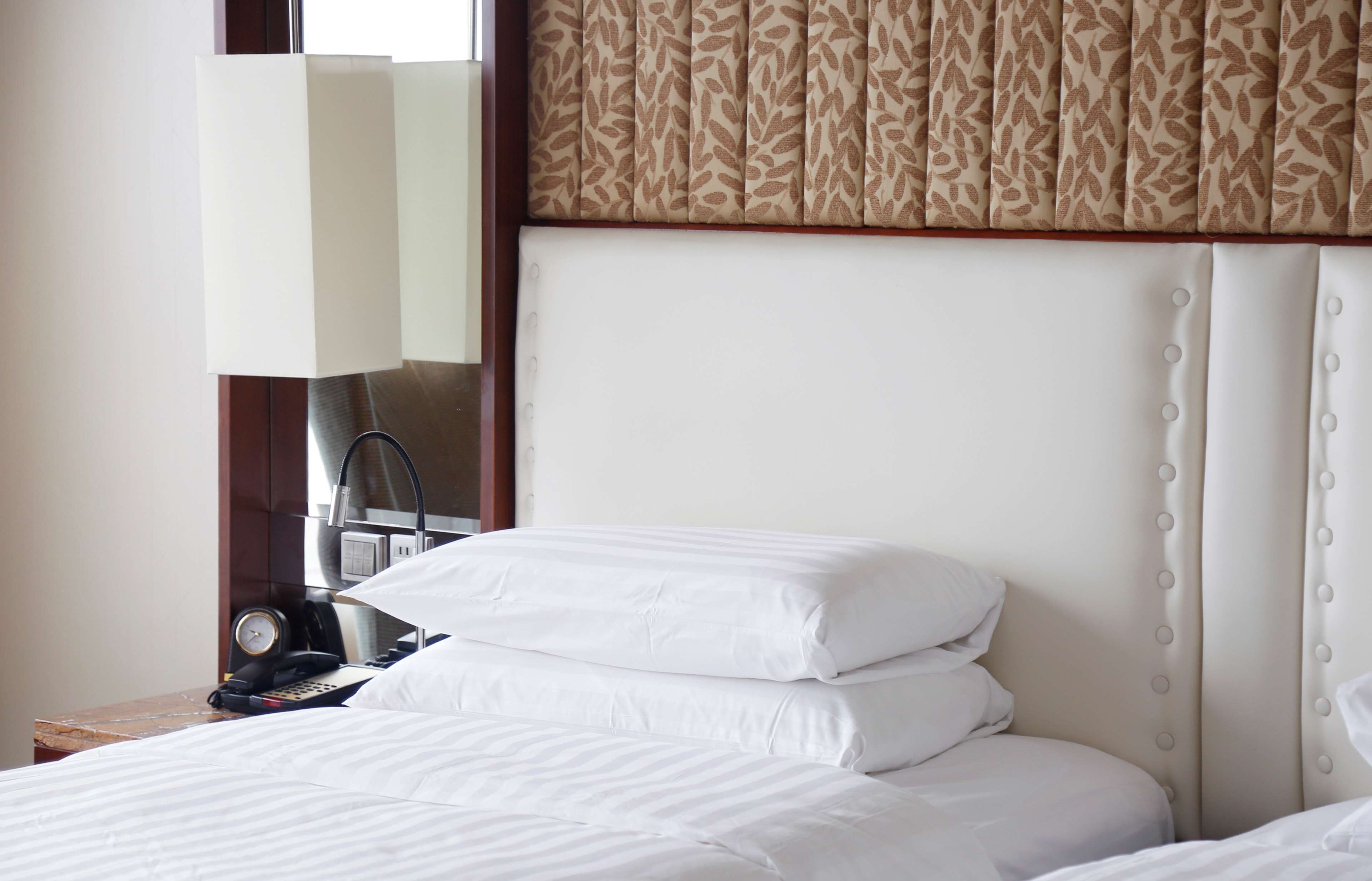 A hotel room with a bed, a nightstand with a lamp, and a mirror.