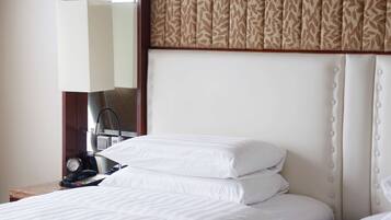 A hotel room with a bed, a nightstand with a lamp, and a mirror.