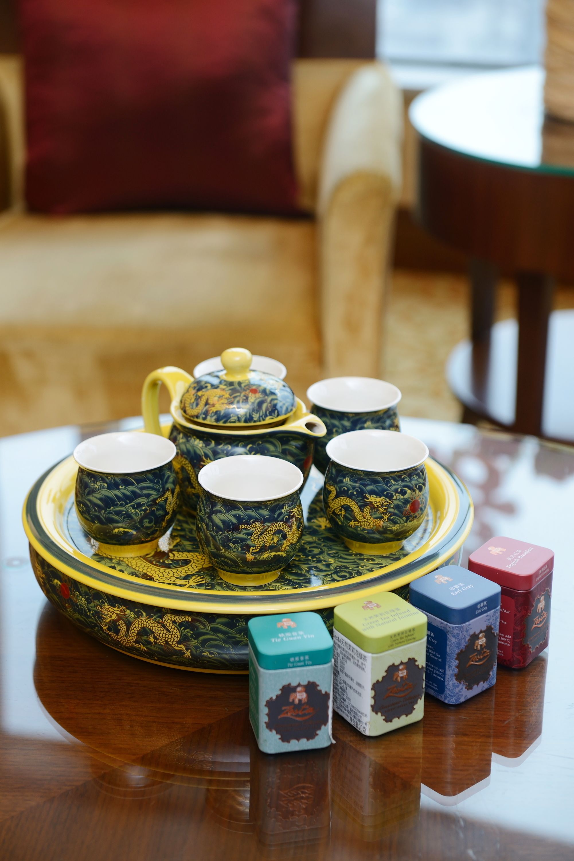 A tray with teacups and a teapot, along with several boxes of tea on a wooden table.