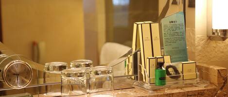 Un'area della reception di un hotel con un bancone in marmo, una sveglia e diversi articoli da toilette e per la cura personale esposti in contenitori trasparenti.
