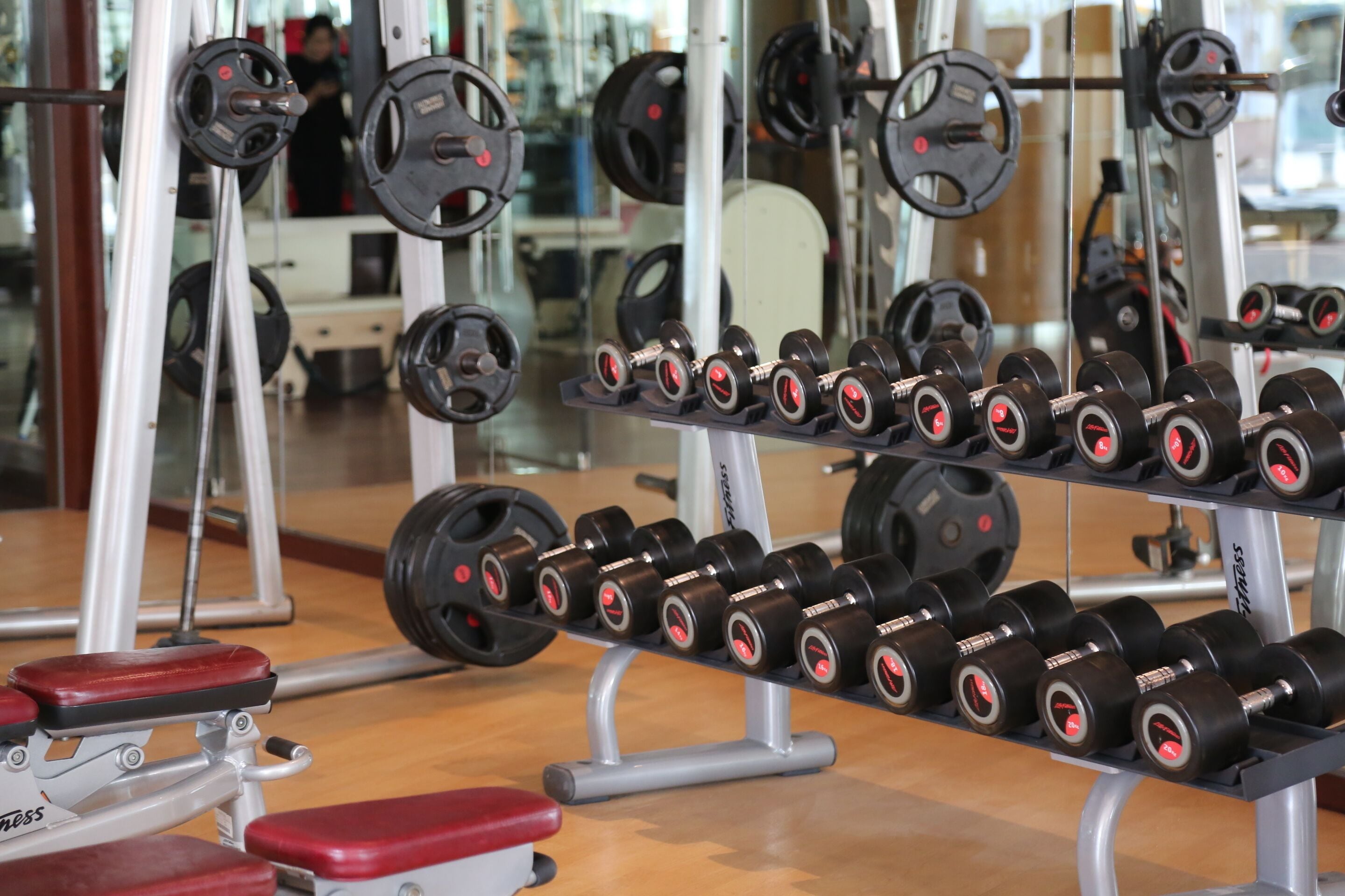 A gym with weightlifting equipment, including dumbbells and barbells.