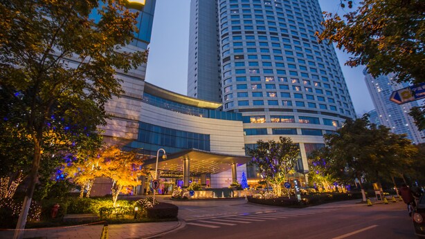 Un hotel moderno con fachada curva, ventanas amplias y un área de entrada bien iluminada.