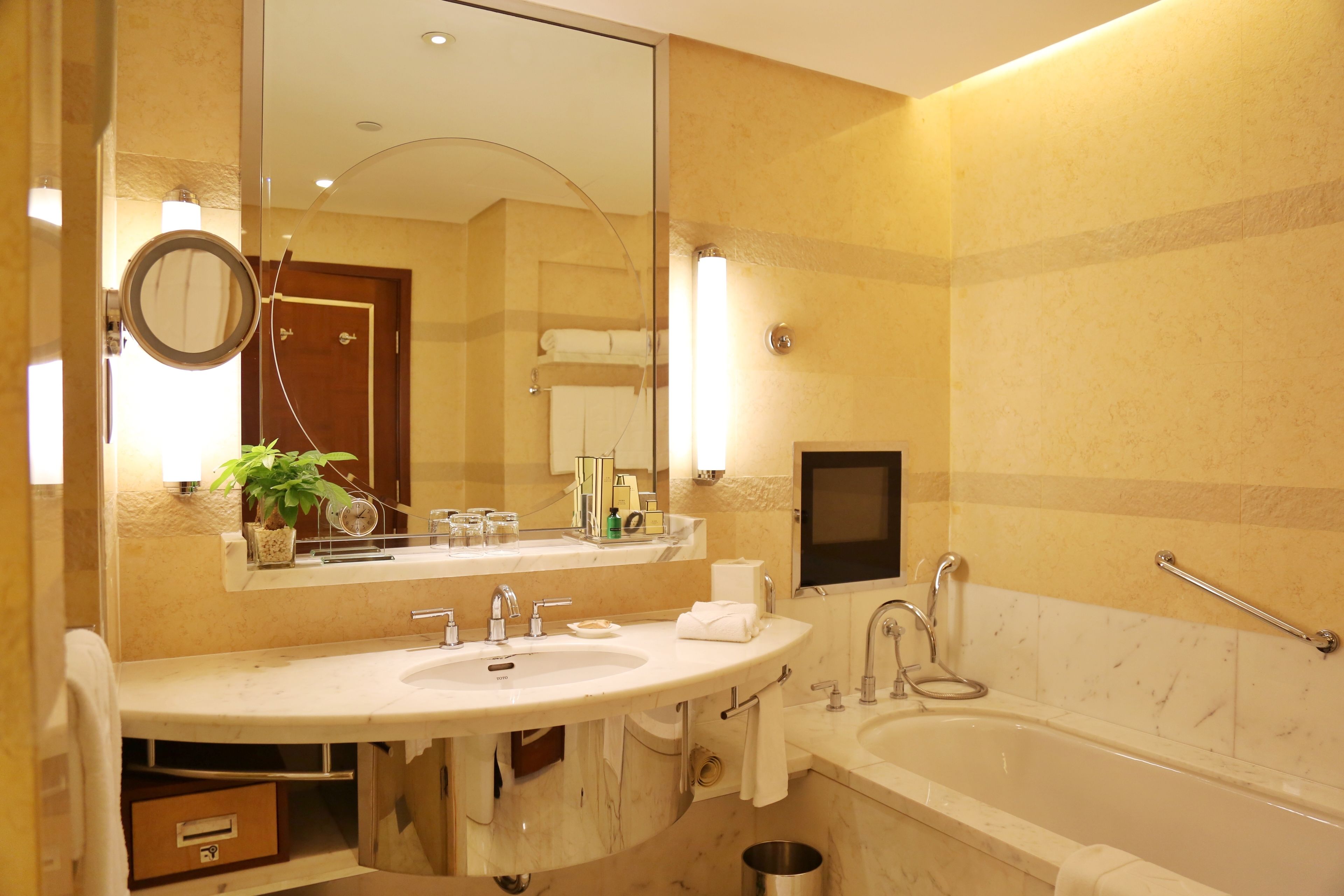 A modern bathroom with a large sink, mirror, and bathtub.