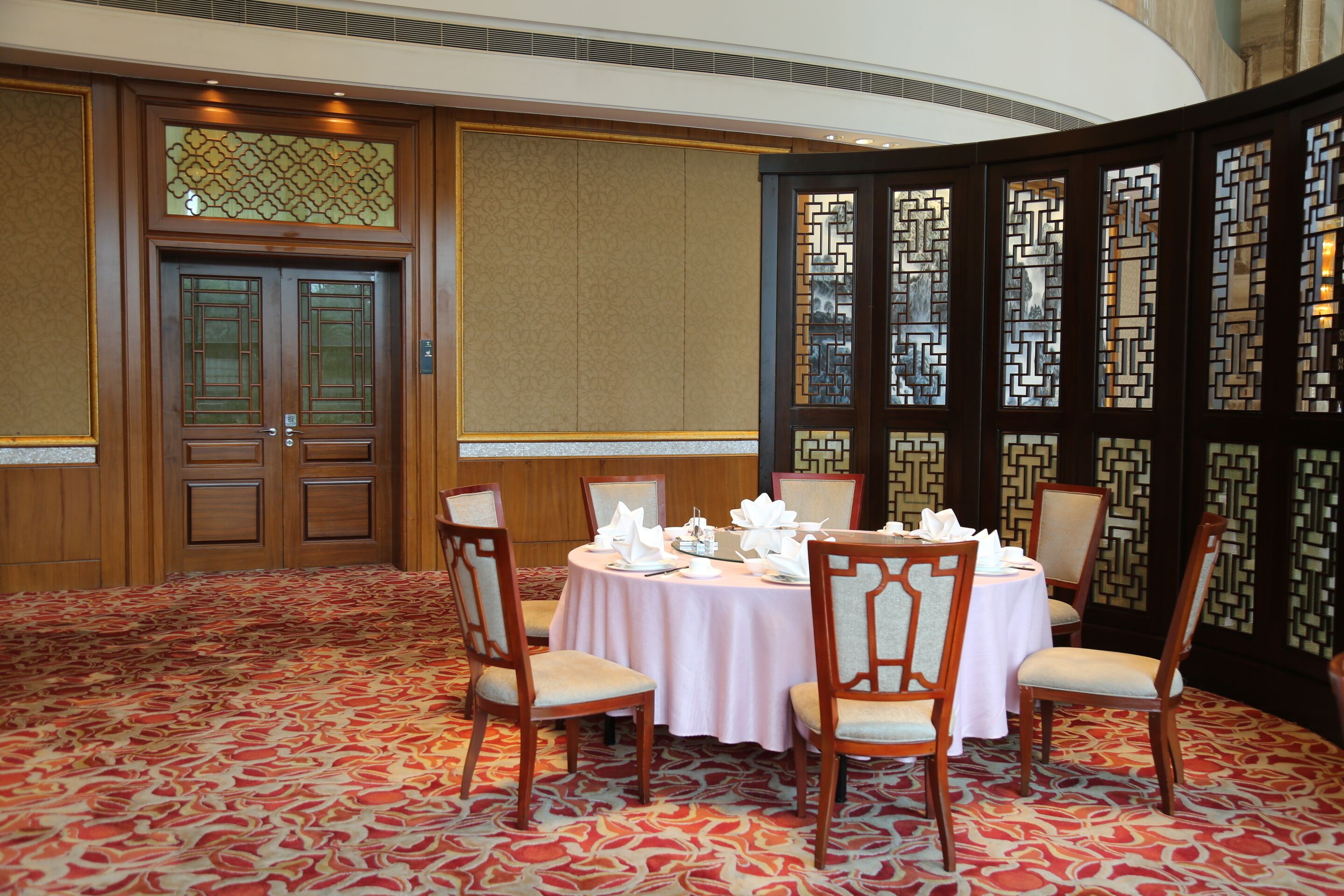 A conference room with a round table, four chairs, and a carpeted floor.