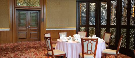 A conference room with a round table, four chairs, and a carpeted floor.