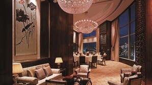 Un lobby de hotel lujoso con una gran araña, muebles elegantes y vistas a la ciudad.