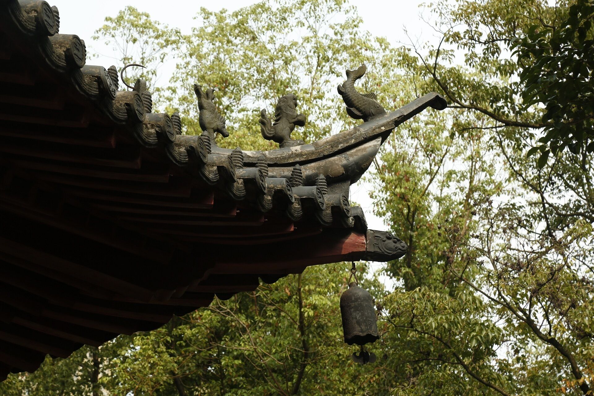 A traditional roof with ornate carvings and a hanging bell.