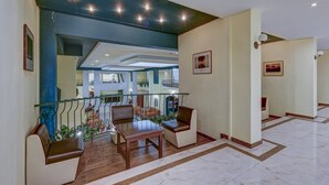 A spacious lobby with a high ceiling, a staircase, and a seating area with a table and chairs. - Shipka (Golden Sands)