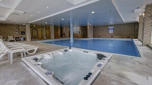 A modern indoor swimming pool with a hot tub, lounge chairs, and stone wall decor. - Shipka (Golden Sands)