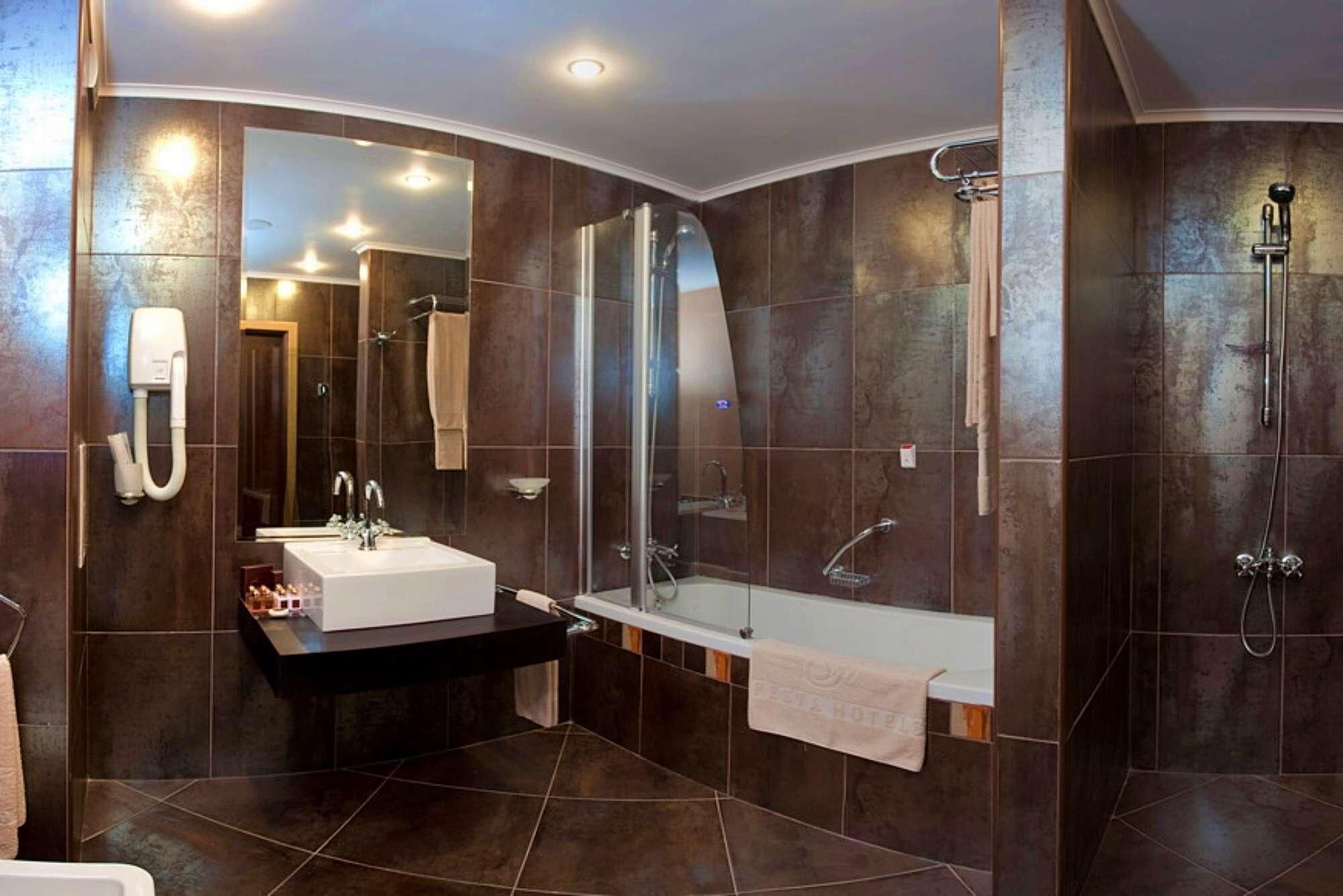 Un baño moderno con un espejo grande, lavamanos, bañera y ducha.