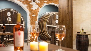 A rustic bar setting with wooden barrels, bottles, and glasses on a table. - Festa Via Pontica (Pomorie)