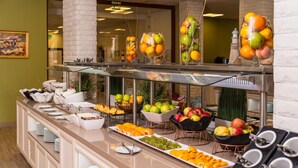 A buffet with various fruits and vegetables, including apples, oranges, and cucumbers, displayed in bowls and on plates. - Festa Via Pontica (Pomorie)