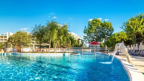 A clear blue swimming pool with a water fountain, surrounded by lounge chairs and trees. - Festa Via Pontica (Pomorie)