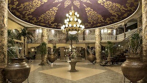 A grand lobby with a large chandelier, ornate columns, and potted plants. - Royal Park Hotel - All Inclusive (Elenite)