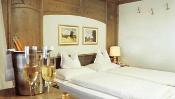 A hotel room with a wooden headboard, two framed pictures on the wall, a bedside table with a lamp, and a bed with white bedding.