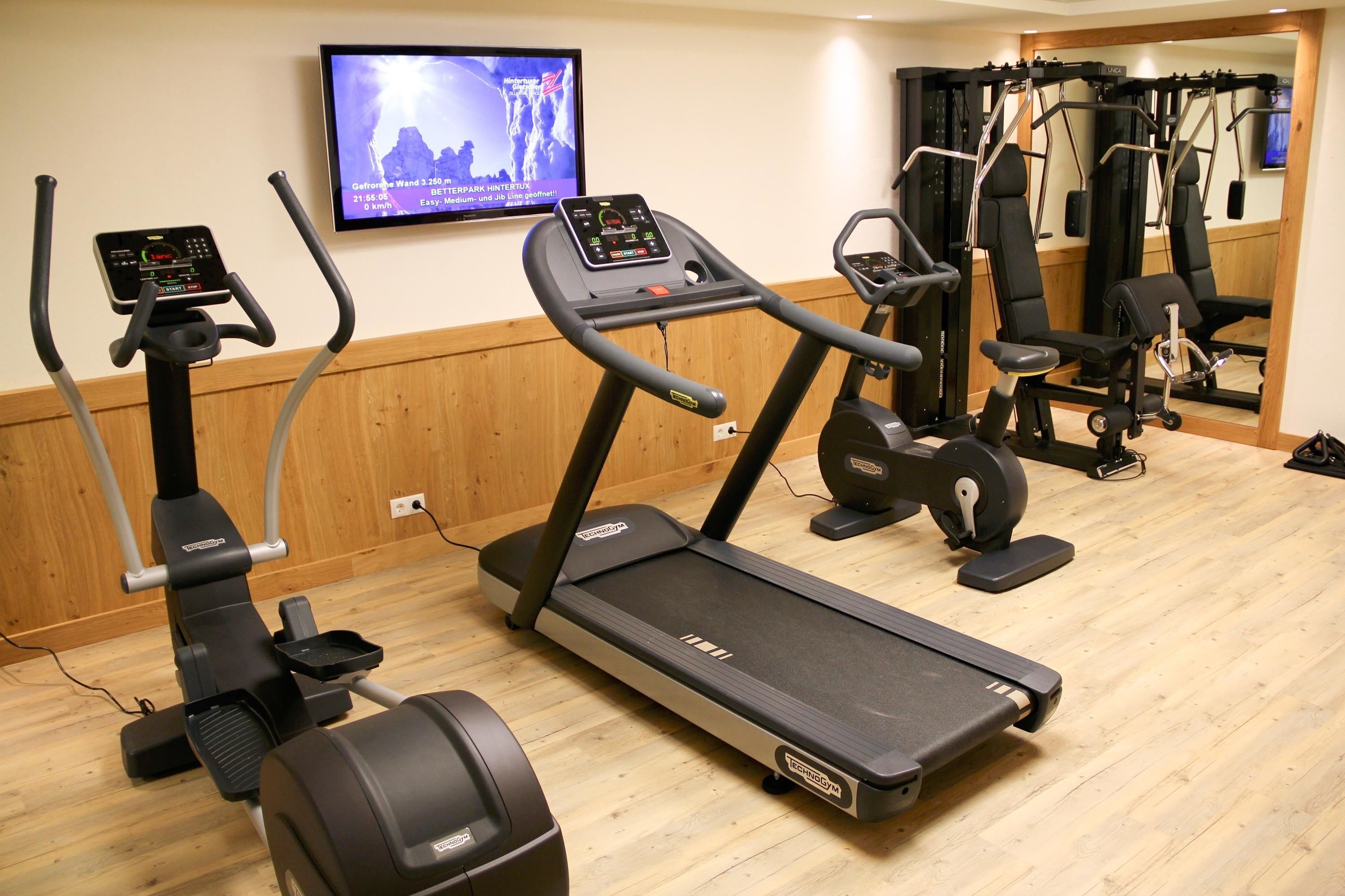 Un gimnasio con cintas de correr, elípticas y máquinas de pesas.