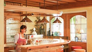 Una zona de bar con mobiliario de madera, una barra y lámparas colgantes.
