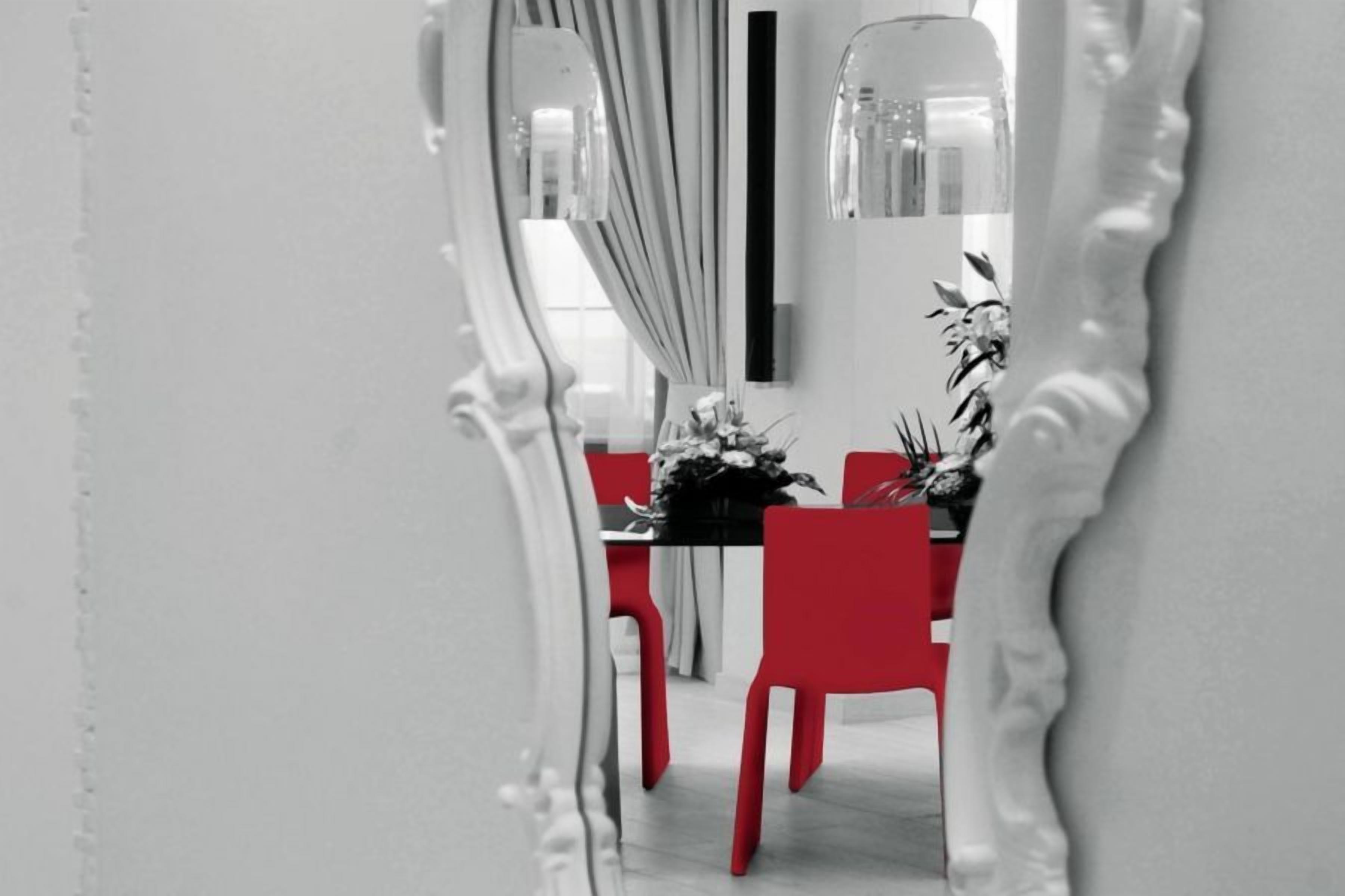 Un espace repas comprenant une table, des chaises et un miroir qui reflète la pièce.