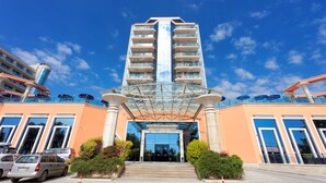 A modern hotel with a glass facade, multiple balconies, and a central entrance with steps. - Astera Hotel & Spa (Golden Sands)