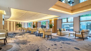A spacious lobby with a high ceiling, large windows, and a carpeted floor. - Regal Jinfeng Hotel (Shanghai)