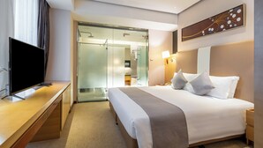 A hotel room with a bed, bedside table, TV, and a walk-in closet. - Regal Jinfeng Hotel (Shanghai)
