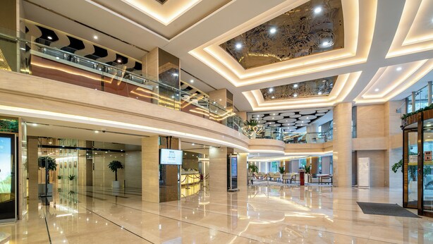 A spacious, multi-level atrium with a modern design, featuring a central open area, upper balconies, and a ceiling with intricate patterns. - Regal Jinfeng Hotel (Shanghai)