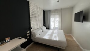 A modern hotel room with a large bed, a bedside table, a flat-screen TV mounted on the wall, and a window with sheer curtains. - Urban Sea Atocha 113 (Madrid)