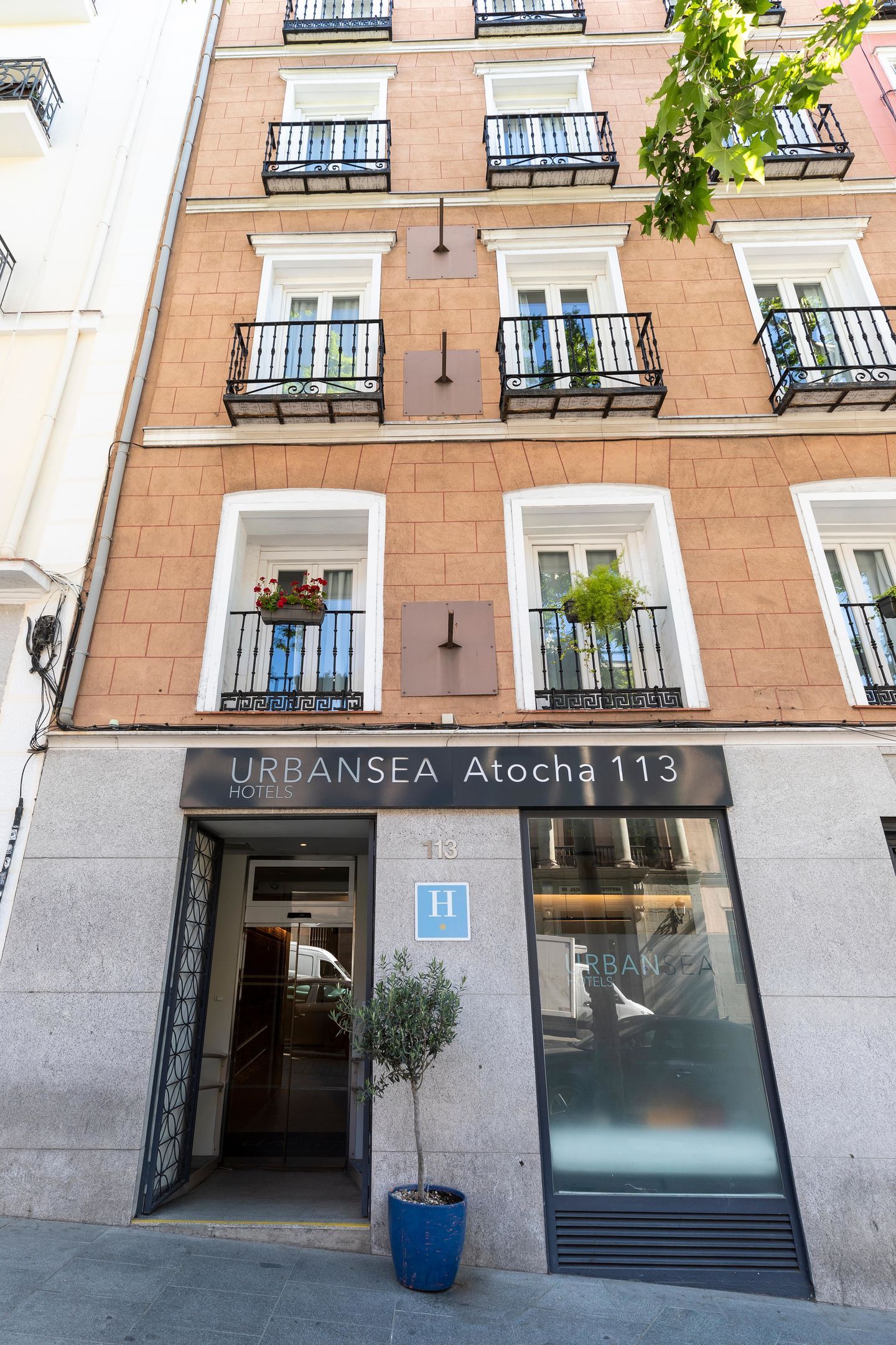 A hotel entrance with a sign reading 'URBANSEA Aloha 113' and a blue 'H' indicating it is a hotel.