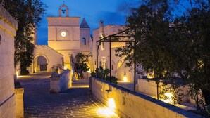 A historic building with a clock tower, a paved courtyard, and a covered walkway. - Borgo Egnazia (Fasano)