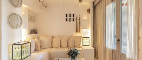 A modern living room with a beige sofa, a coffee table with fruits and a vase, and decorative items on the walls.