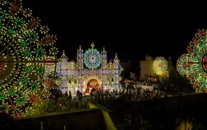 A large, illuminated building with intricate designs and a crowd of people gathered in front. - Borgo Egnazia (Fasano)