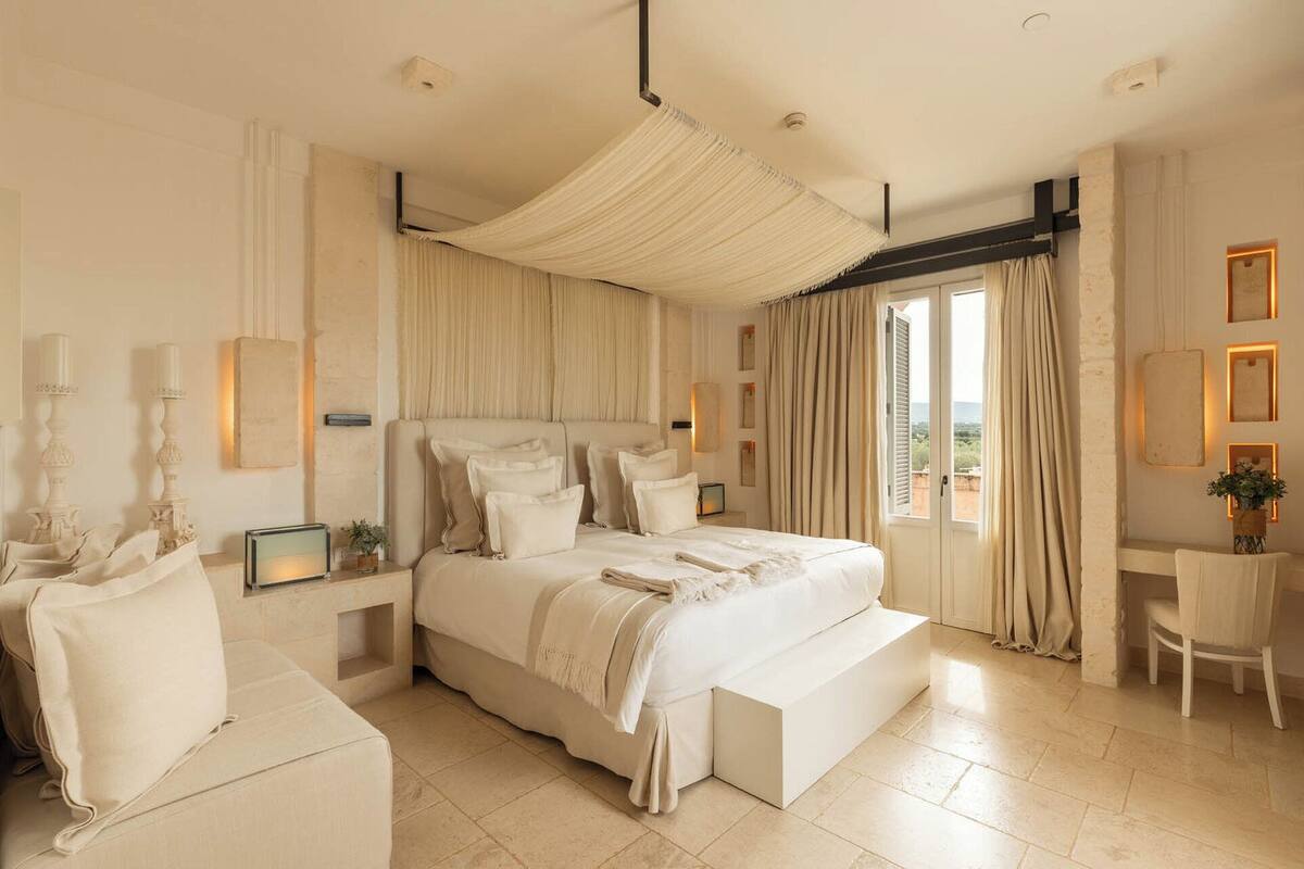 A spacious bedroom with a large bed, a canopy, and a view of the outdoors.