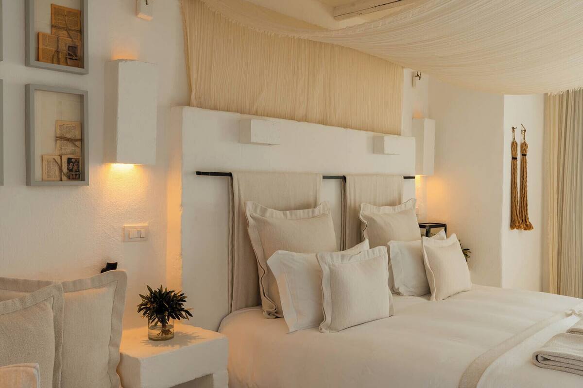 A modern bedroom with a large bed, white bedding, and a ceiling with a textured design.