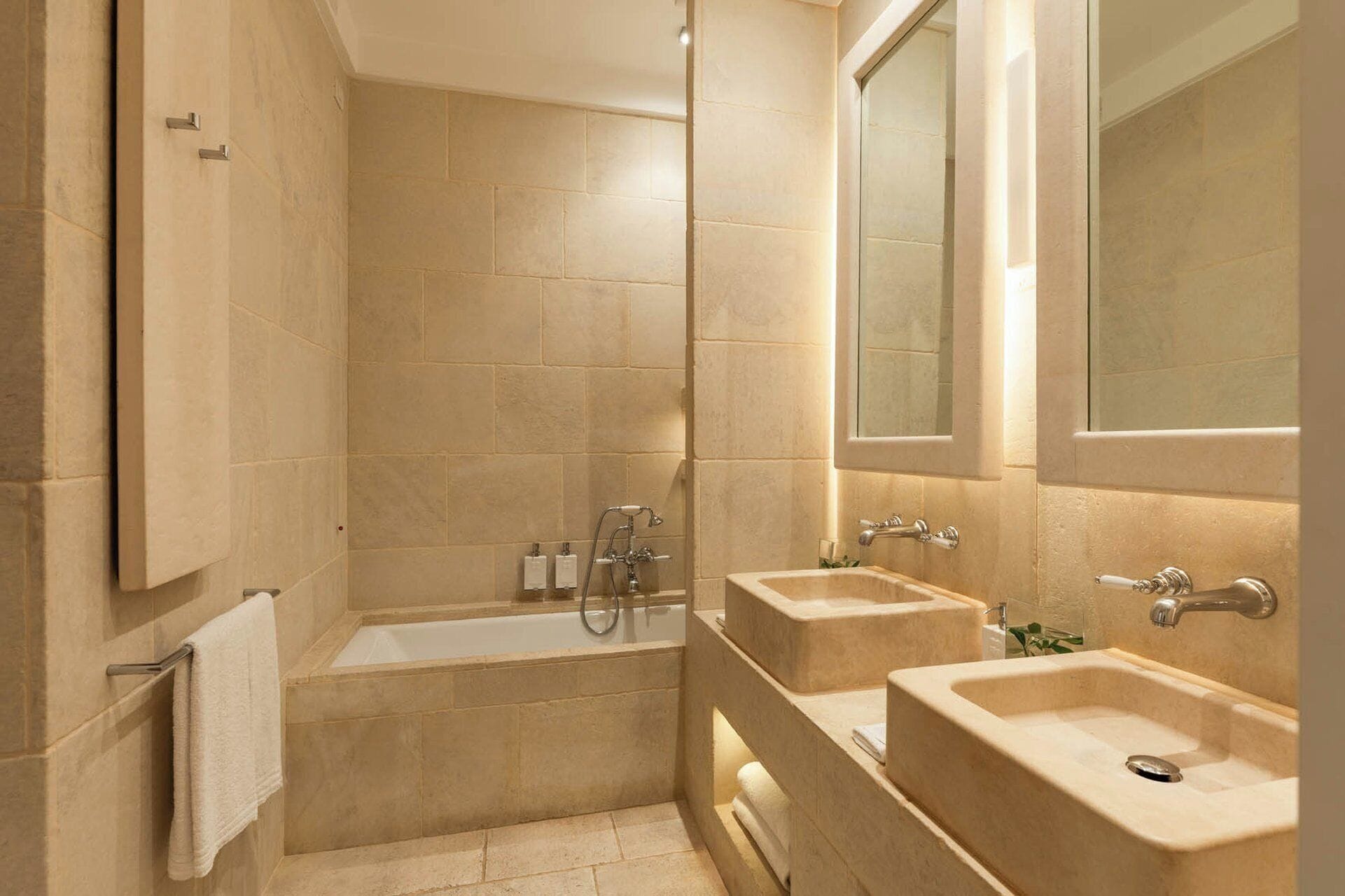 A bathroom with a bathtub, two sinks, and a mirror.