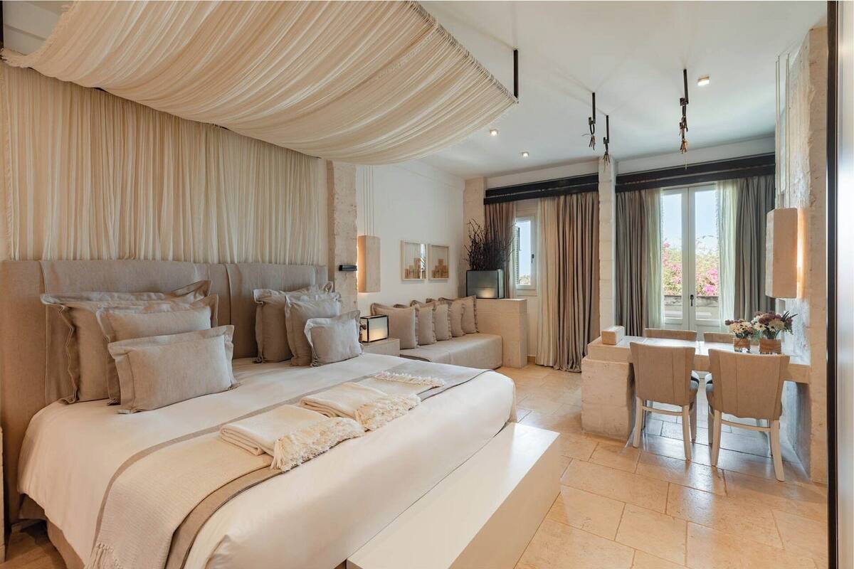 A spacious bedroom with a large bed, a sitting area, and a desk with chairs.