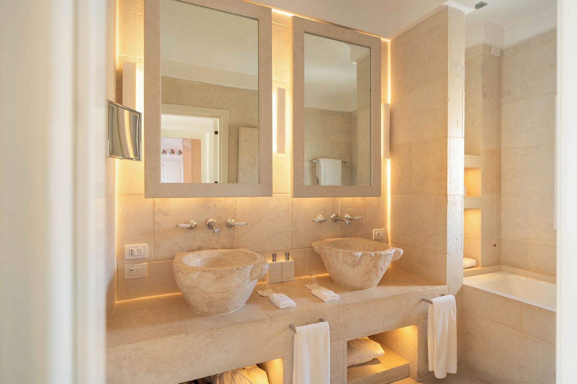 A bathroom with two stone sinks, a large mirror, and a bathtub.